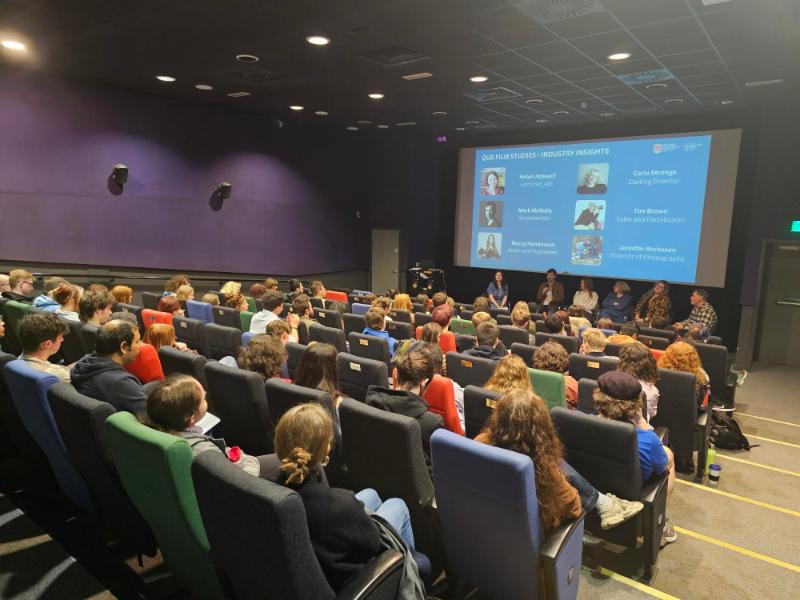 A group of students sitting in a cinema watching a presentation on the screen